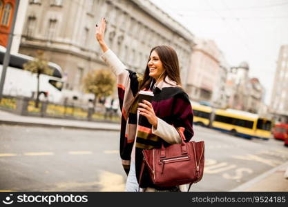 View at young woman hailing a taxi on the street in the city