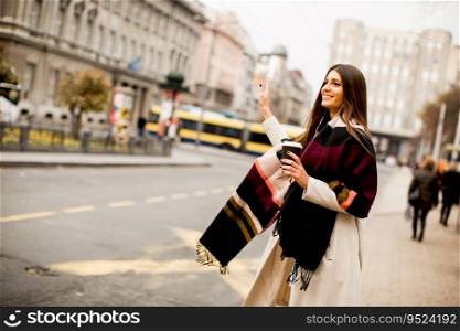 View at young woman hailing a taxi on the street in the city