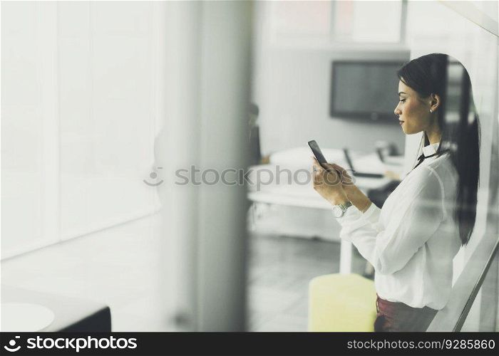 View at young woman using mobile phone in the office