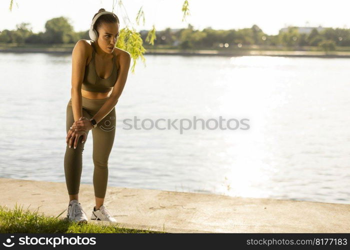 View at young woman with headphones  taking a break during exercising outside