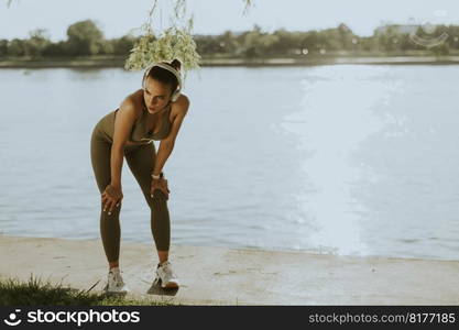 View at young woman with headphones  taking a break during exercising outside