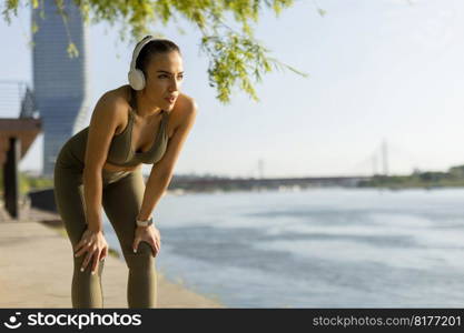 View at young woman with headphones  taking a break during exercising outside