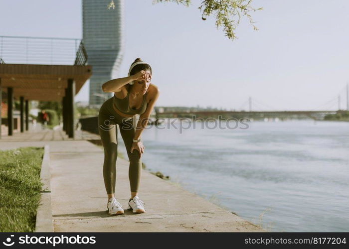 View at young woman with headphones  taking a break during exercising outside