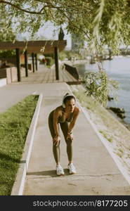 View at young woman with headphones  taking a break during exercising outside