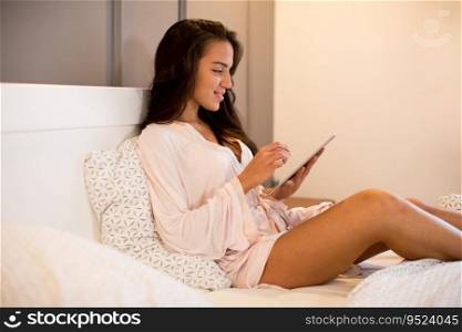 View at young woman with tablet in bed