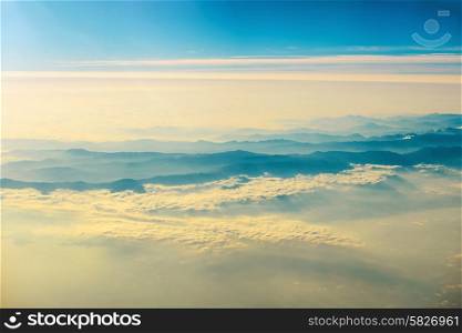 View from a plane to sunset on the sky with sunrays. Fluffy clouds background