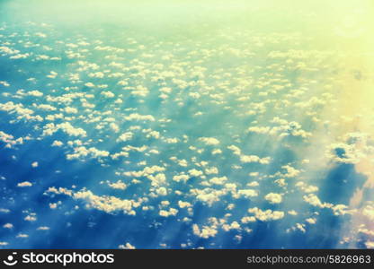 View from a plane to sunset on the sky with sunrays. Fluffy clouds background