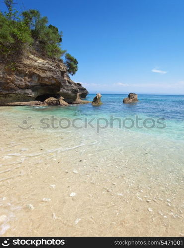 View from a sandy beach on rocks at ocean. Indonesia, Bali