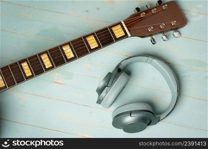 view from above of guitar and green headphones on wooden background, closeup