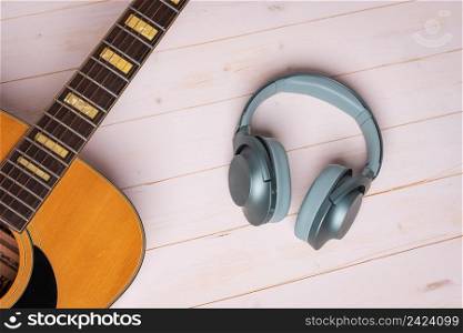 view from above of guitar and green headphones on wooden background, closeup