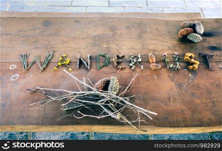View from above of wanderlust word made with natural objects over wooden table. Wanderlust word made with natural objects over table