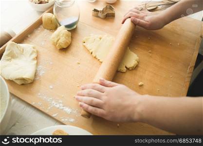 View from above of woman rolling dough with wooden pin