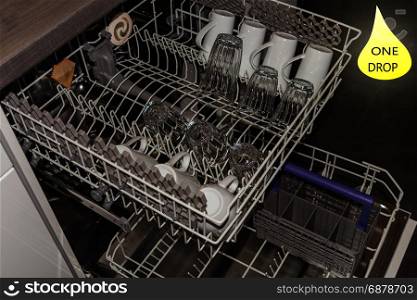 View from above on an open dishwasher with clean cup, glasses and plates.