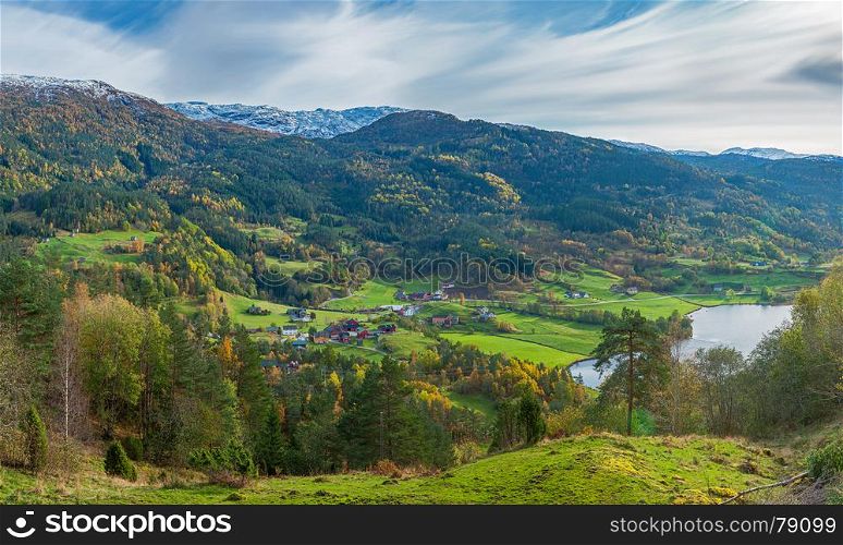 View from above on small mountain valley and distant norwegian village near fjord