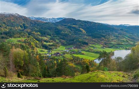 View from above on small mountain valley and distant norwegian village near fjord