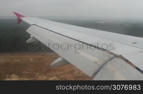View from aircraft window. Airplane landing in airport. Landscape as seen from jet wing from window while airplane going to land.