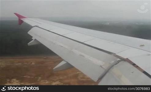View from aircraft window. Airplane landing in airport. Landscape as seen from jet wing from window while airplane going to land.