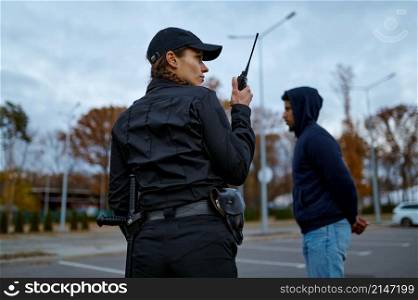 View from back on woman cop in uniform using portable radio for police communication. Woman cop using portable radio back view