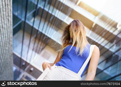 View from below of young girl moving her hair wild outdoors. View from above of young girl moving her hair wild