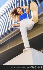 View from below of young girl throwing her foot in the air in urban background.. View from below of young girl throwing her foot in the air.