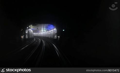 View from driver window of Paris metro subway and station lights around curve in background. Paris metro subway with station in background