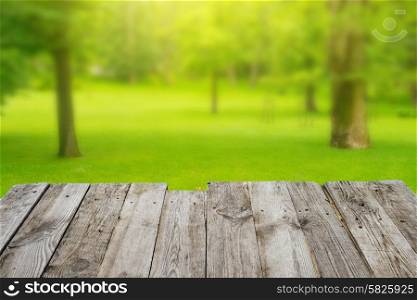 View from empty wooden deck table to the green spring foliage bokeh background