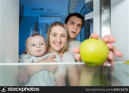 View from inside the refrigerator on smiling family looking for something to eat