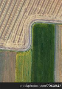 View from the height of a bird’s flight from flying drones to agricultural fields, prepared for sowing crops. Top view.. Abstract geometric background of agricultural fields with different crops and soil without crop sowing, separated by road
