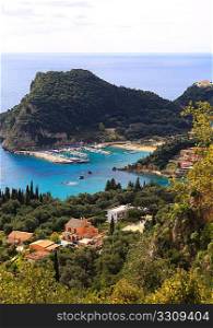 View from the mountain above of Paleokastritsa harbour, Corfu, with Paleokastritsa monastery top right. The sandy bays are among the Ionian island&acute;s top tourist attractions. Vertical composition
