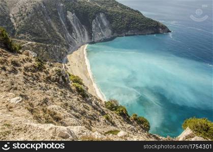 view from the mountain of myrtos beach and the fascinating variations of sea tones caused by the dust generated by the sea eroding the stones that fall from the mountains that surround it