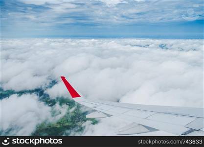 View from the plane window,Wing of an airplane flying above the clouds with blue sky.