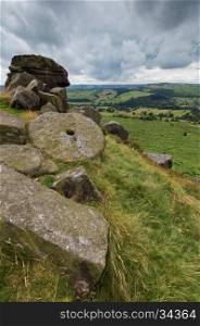 View from the top of a hill at Baslow Edge, in the Peak District, Derbyshire, with a mill stone in the foreground