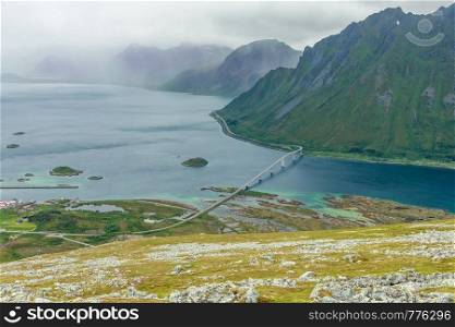 View from the top of Kleppstadheia mountain to the bay with turquoise water, and Rystad and bridge highway between two islands, Austvagoya, Lofotens, Norway