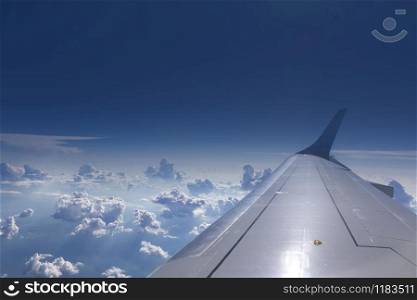 View from the window of airplane on an aircraft wing on a background of blue cloudy sky in a sunny day. Place for your text. Travel and transportation concept.. Wing of aircraft on a background of clear blue sky.