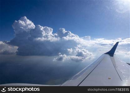 View from the window of airplane to aircraft wing on a background of blue cloudy sky and bright sun. Place for your text. Travel and tourism concept.. Wing of aircraft on a background of clear blue sky.
