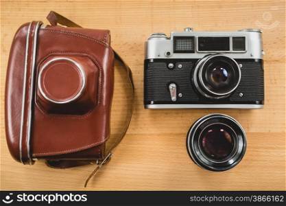 View from top of retro photography set of camera, case and lens on wooden background