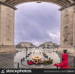 View from under the Arch of Triumph, over the Eternal Flame, the monument for the unknown soldier and Champs-Elysees boulevard, on a gloomy, rainy day.
