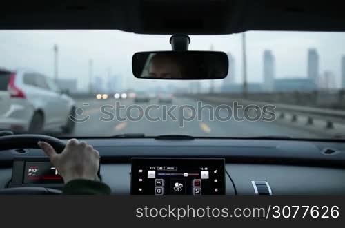 View inside out. Female driver driving her automobile over the bridge in the city during rush hour. Blurred traffic in the city road. Real life transportation in modern city concept.