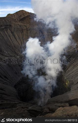 View into volcanic crater of active volcano Bromo with steam and smoke