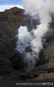 View into volcanic crater of active volcano Bromo with steam and smoke