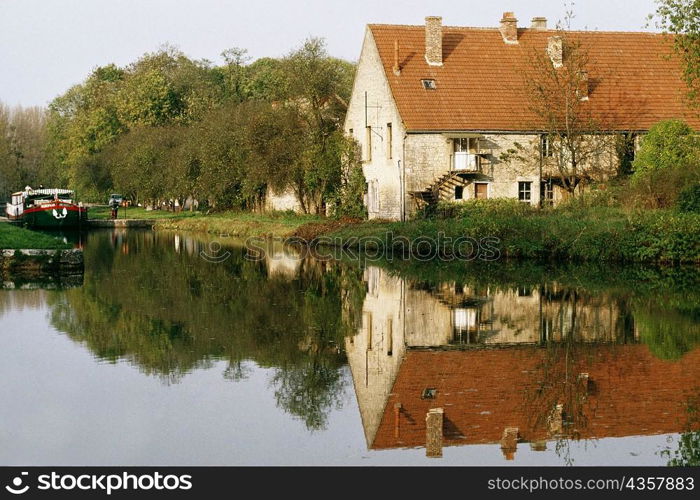 View of a barge moving upstream and passing by a farmhouse, Burgundy River, France