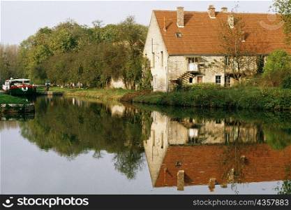 View of a barge moving upstream and passing by a farmhouse, Burgundy River, France
