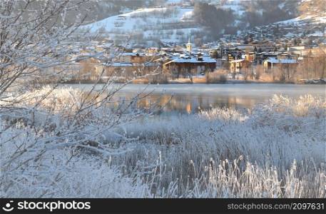view of a city of Savoy, Bourg Saint Maurice, on the banks of a river with frozen trees and plants. view of a city of Savoy on the banks of a river with frozen trees and plants