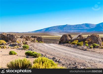 View of a road passing through agricultural field to a mountain with a Vicuna stall at the sideway in Uyuni, Bolivia