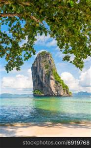 view of a rock in the sea from under the foliage of a tree on Poda Island, Thailand