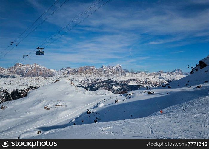View of a ski resort piste with people skiing in Dolomites in Italy with cable car ski lift. Ski area Arabba. Arabba, Italy. Ski resort in Dolomites, Italy