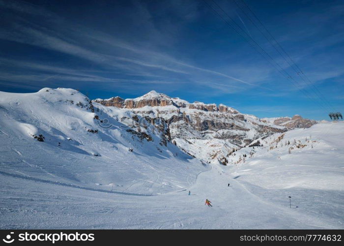 View of a ski resort piste with people skiing in Dolomites in Italy with cable car ski lift. Ski area Arabba. Arabba, Italy. Ski resort in Dolomites, Italy