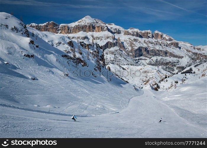 View of a ski resort piste with people skiing in Dolomites in Italy. Ski area Arabba. Arabba, Italy. Ski resort in Dolomites, Italy