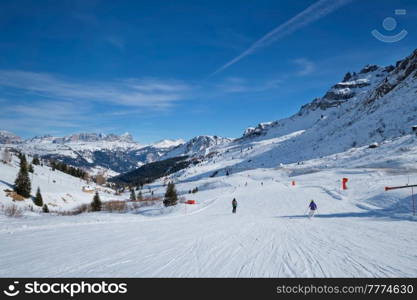 View of a ski resort piste with people skiing in Dolomites in Italy. Canazei, Italy. Ski resort in Dolomites, Italy