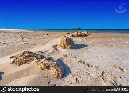 View of a small island from the Israeli shore of the Mediterranean Sea. Sand blowing over beach dune in wind in Israel